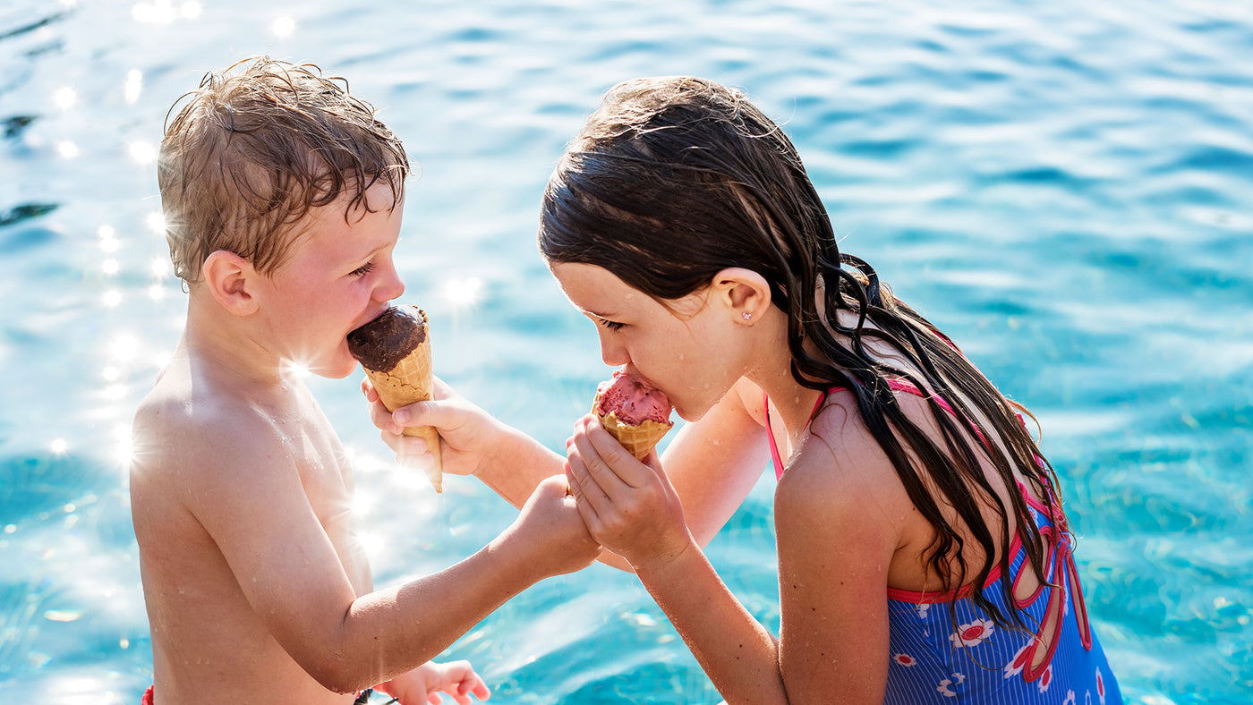 kids standing next to each other in pool and sharing ice cream